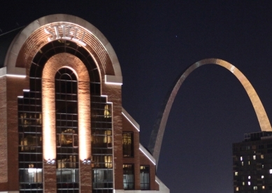 Night shot of Stifel building against the lit up St. Louis Arch